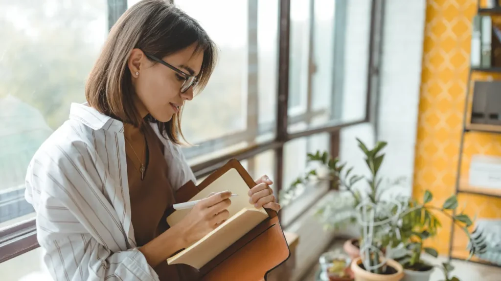 Lady is writing on notebook. 