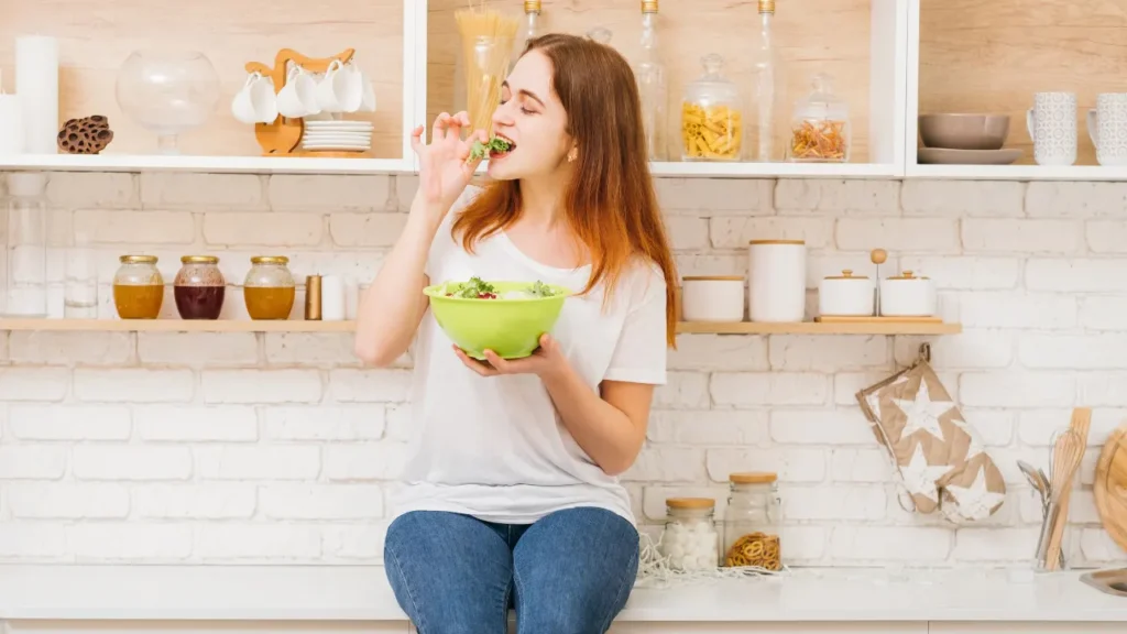 Young girl is eating salad. 